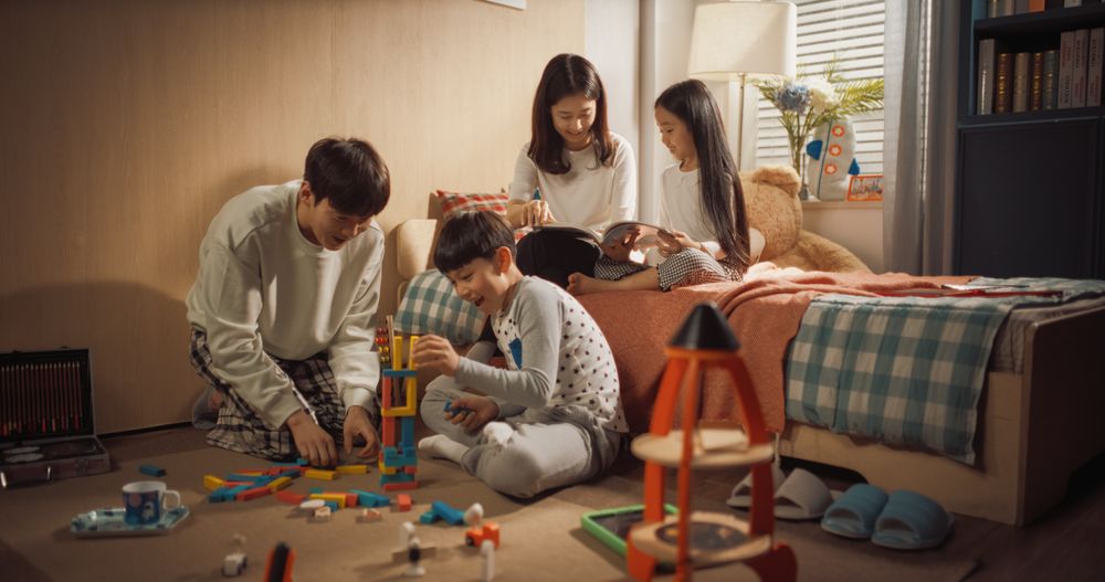 Happy Korean Family Playing Together in Children's Room.