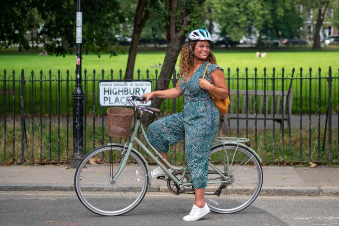 Smiling Black woman stopped with bike next to park