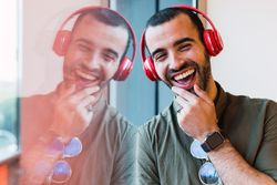 Cheerful man listening to music near window