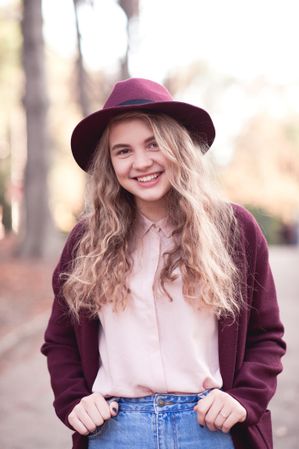 Smiling teenage girl in purple coat with hat standing outdoor