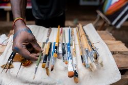 Black artist choosing among a collection of paint brushes