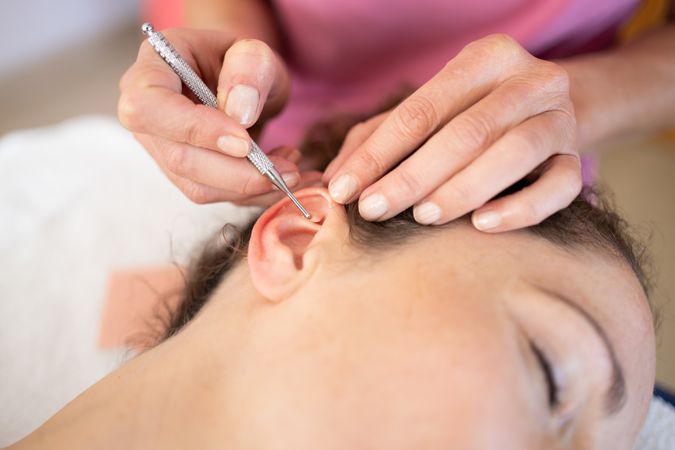 Client of therapist having an auriculotherapy treatment in her ear