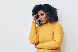 Black woman holding hand to her temple expressing frustration