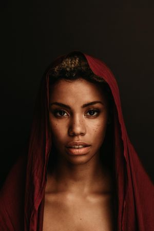Close up of Black woman with a maroon cloth over head