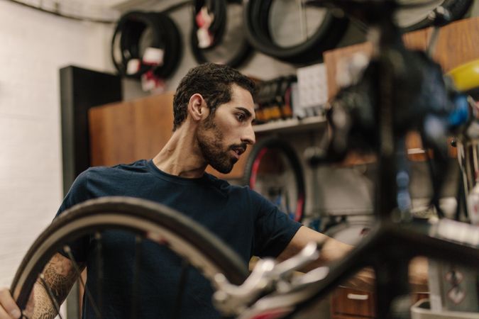 Side view of man fixing bicycles in repair shop