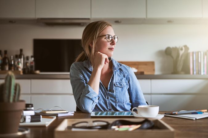 Woman gazing out of window from kitchen table