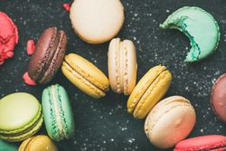 Assortment of multi-colored macaron pastries against a dark background