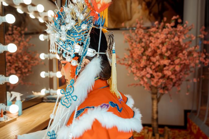 Side view of Chinese actress in her cultural outfit sitting beside mirror
