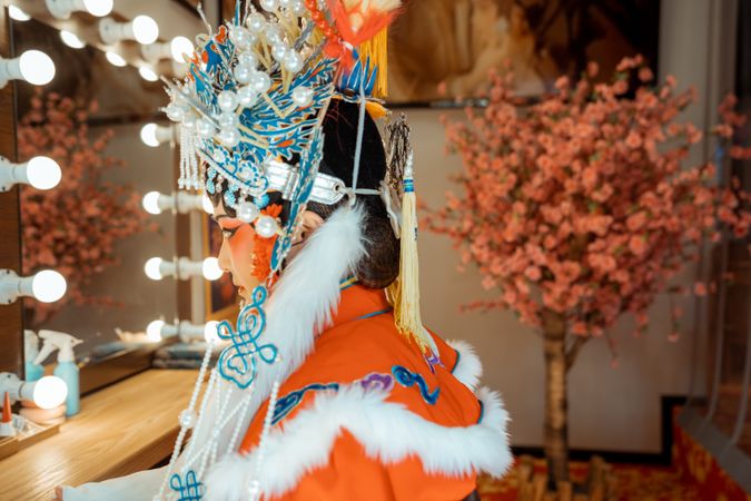 Side view of Chinese actress in her cultural outfit sitting beside mirror