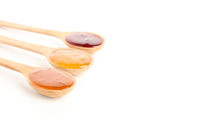 Spoons with jam isolated on plain background