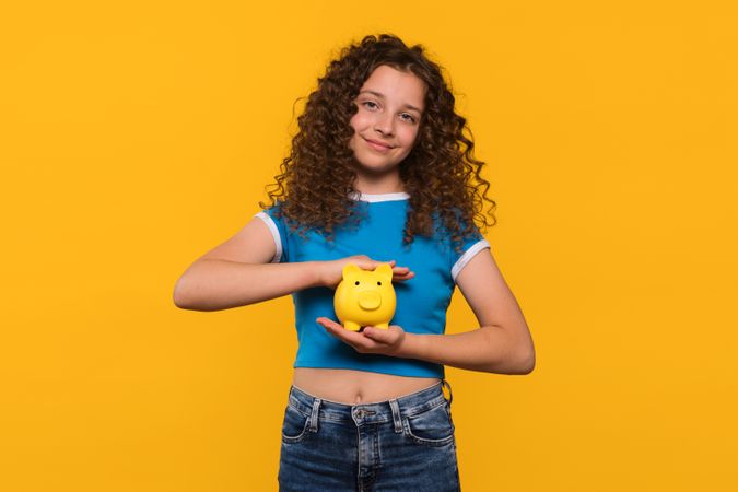 Girl smiling and holding a piggy bank