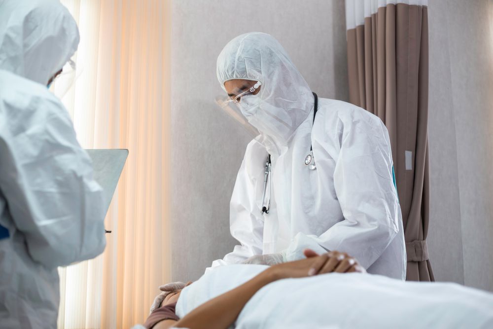 Emergency doctor in PPE checking vitals of patient