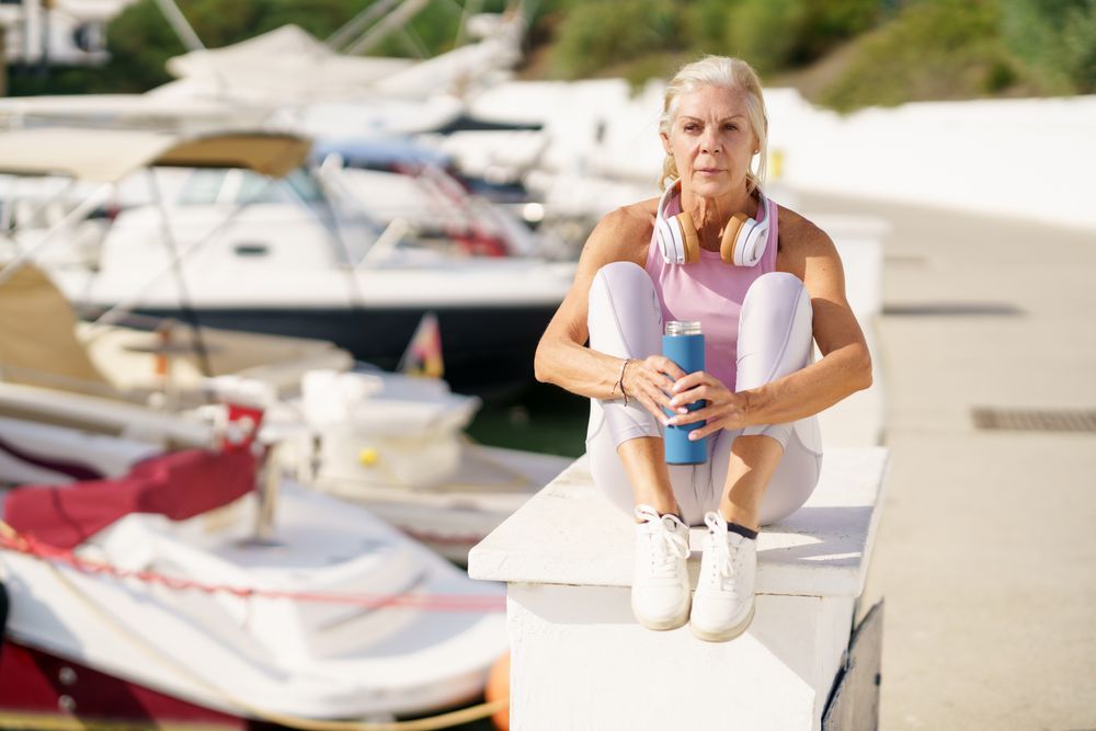 Mature female in sports clothing drinking water from a metal water bottle