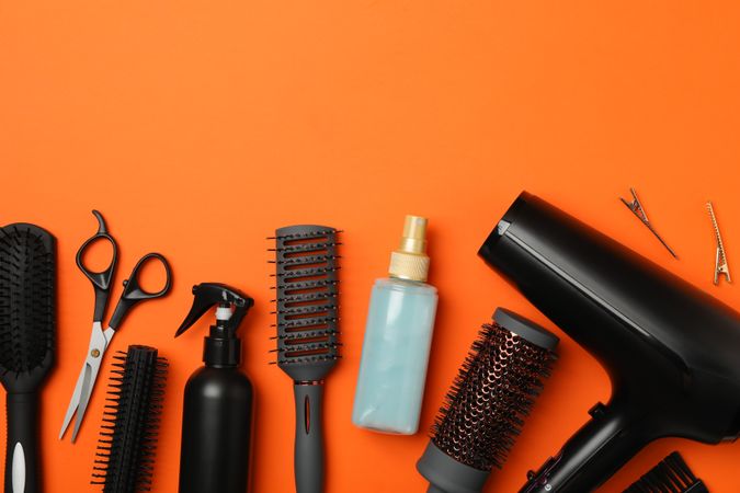 Composition with hairdresser accessories on orange background, space for text