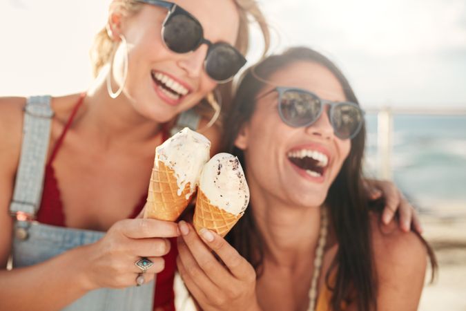 Two young female friends having fun and eating ice cream
