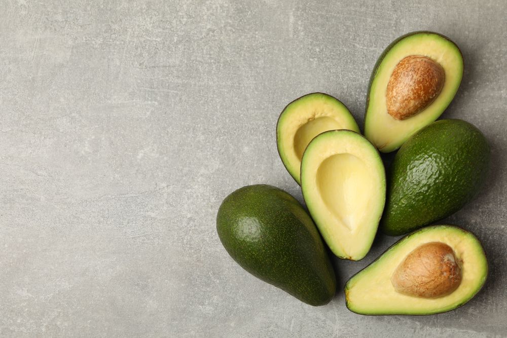 Ripe fresh avocado on gray background, space for text