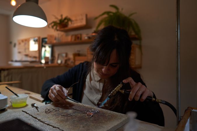 Focused female artisan creating handmade accessories in workshop