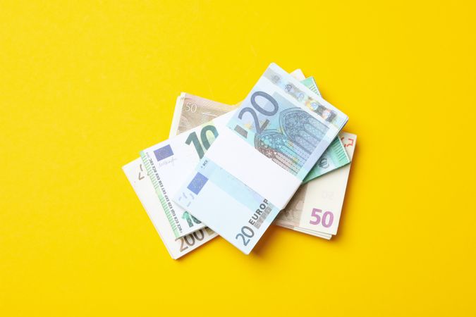 Many bundles of euros on a yellow background.