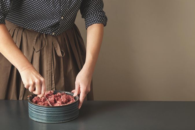 Woman mixing ground beef with spoon in bowl