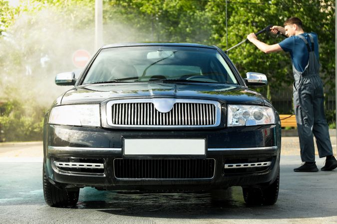 A man washes a car in a manual car wash. Clear car