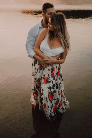 Loving couple hugging while standing ankle deep in water on beach