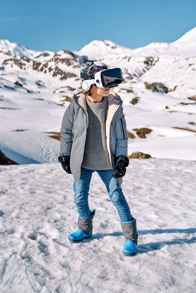 Boy in VR goggles in snowy mountains