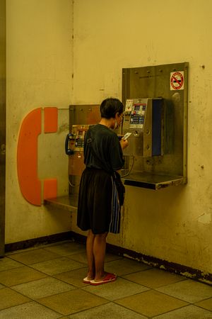 Back view of woman using public telephone