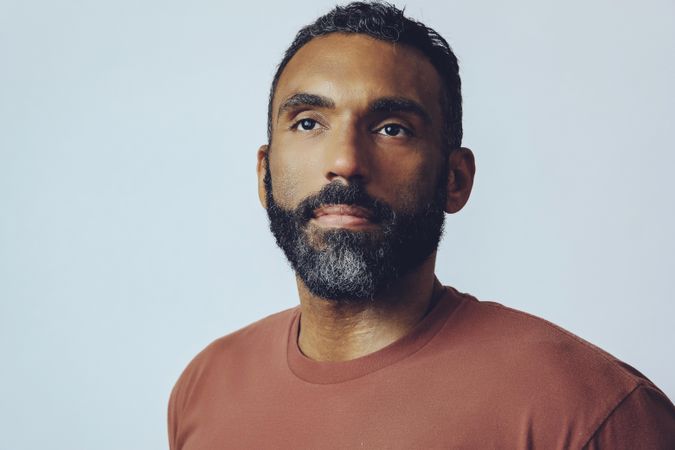 Head shot of serious Black male looking up in grey studio, copy space