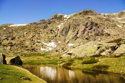 Clear lake at bottom of rocky mountain
