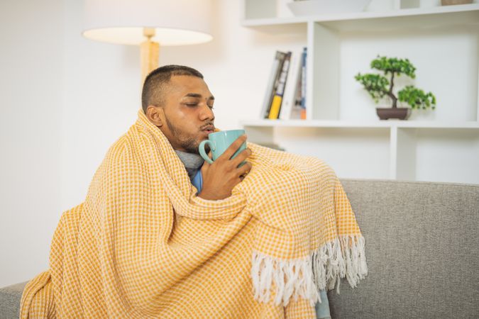 Young man with the flu, drinking a cup of tea