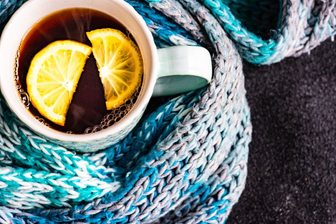 Top view of tea time concept with teal scarf wrapping around cup of tea