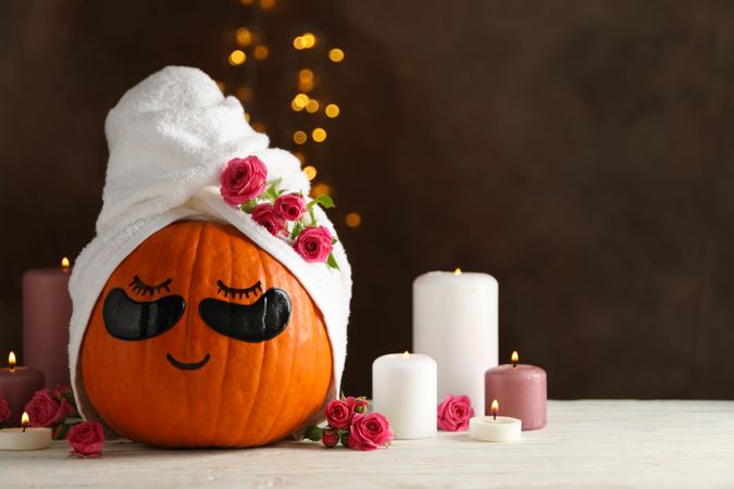 Candles and pumpkin with eye patches on brown background