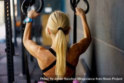 Back of blonde woman using gymnastic bars in gym 47mx7a