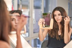 Woman with mirror applying makeup