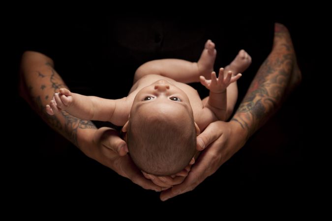 Hands of Father and Mother Hold Newborn Baby