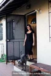 Full length portrait of woman in dark dress standing at her front porch with her dog 0Pjpr4