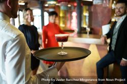 Bartender with red cocktail on serving tray 0K1aA4