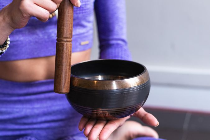Anonymous woman playing singing bowl during yoga session