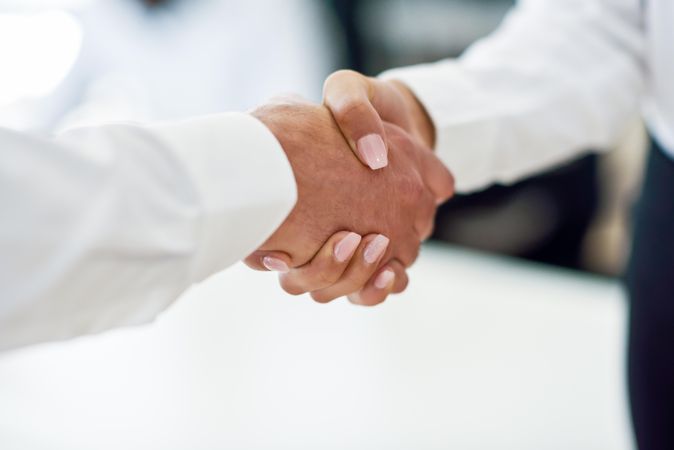 Close up of male and female shaking hands in professional setting