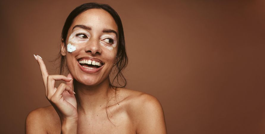 Smiling woman applying facial cream