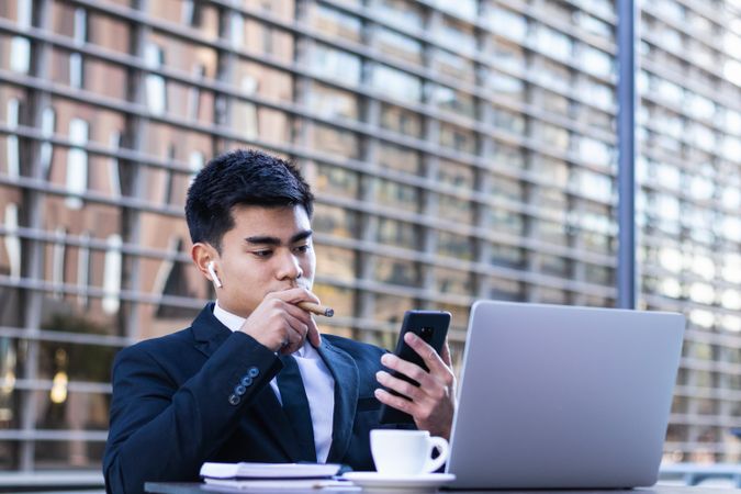 Businessman smoking cigar in street cafe