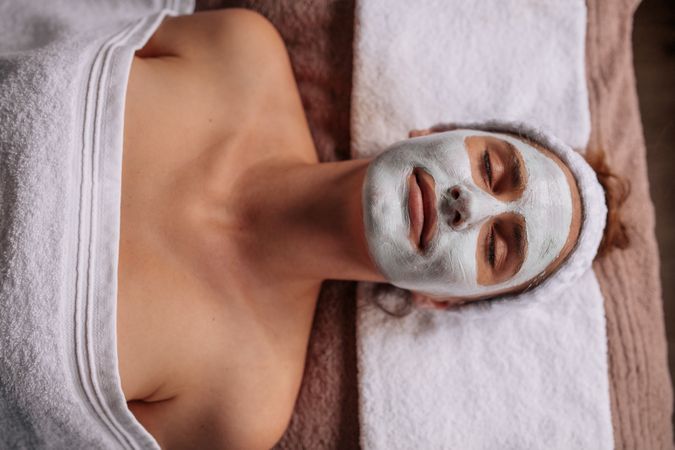 Woman with facial mask lying on spa table