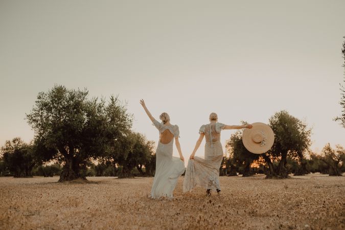 Slim brides in lace dresses holding hands