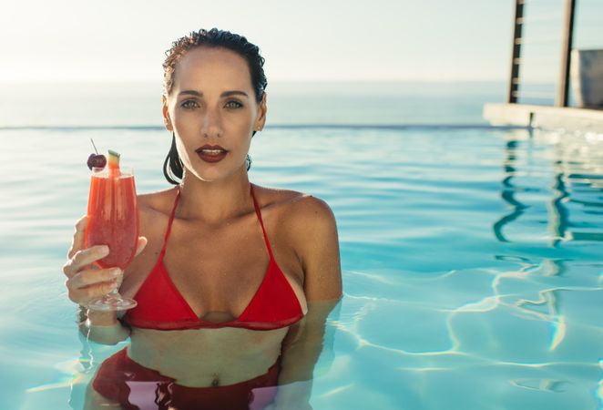 Attractive female enjoying cocktail at resort pool