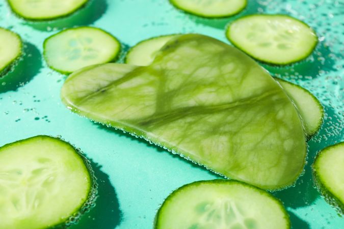 Slices of cucumber in sparkling water with a jade face massager