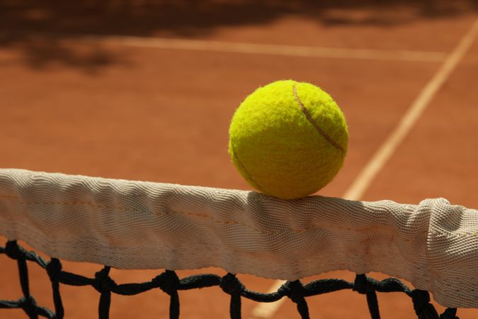 Clay tennis court, net with ball, close up