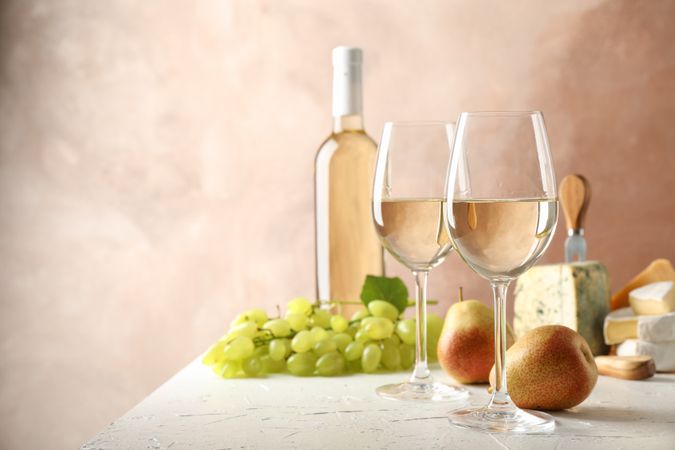 Grape, cheese, pears, glasses and bottle with wine, on plain background, copy space