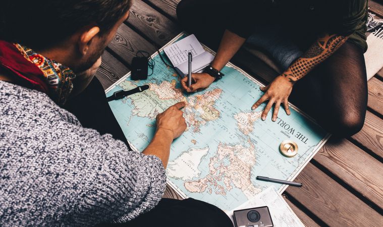 Two people pointing at world map