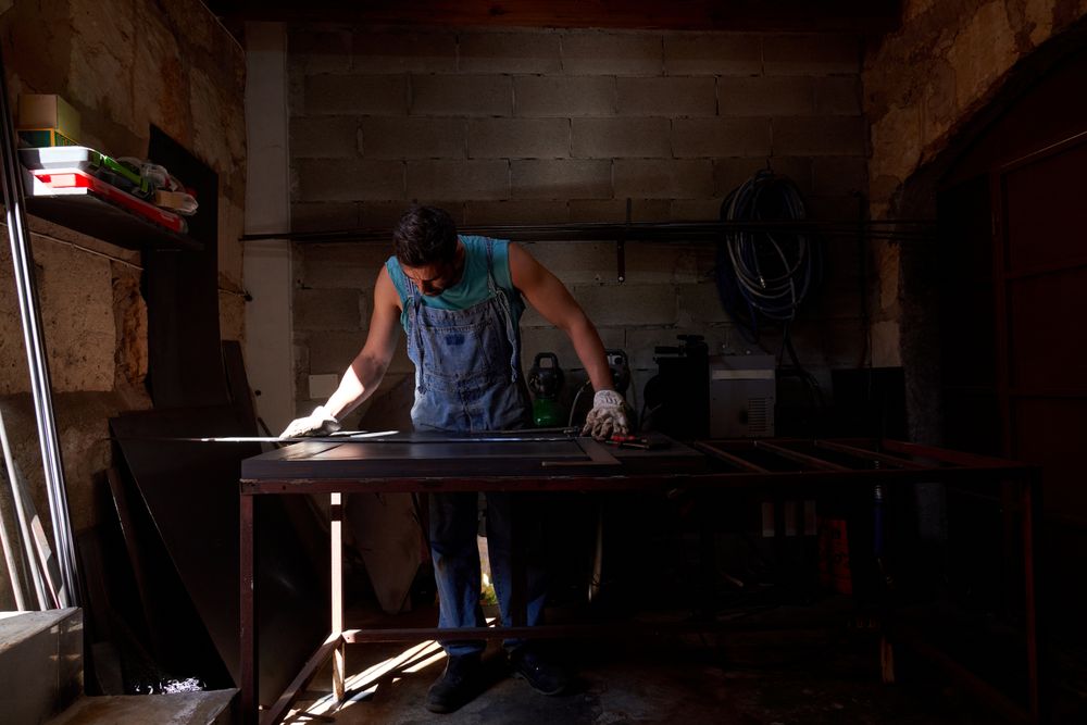 Focused male artisan measuring metal sheet in garage