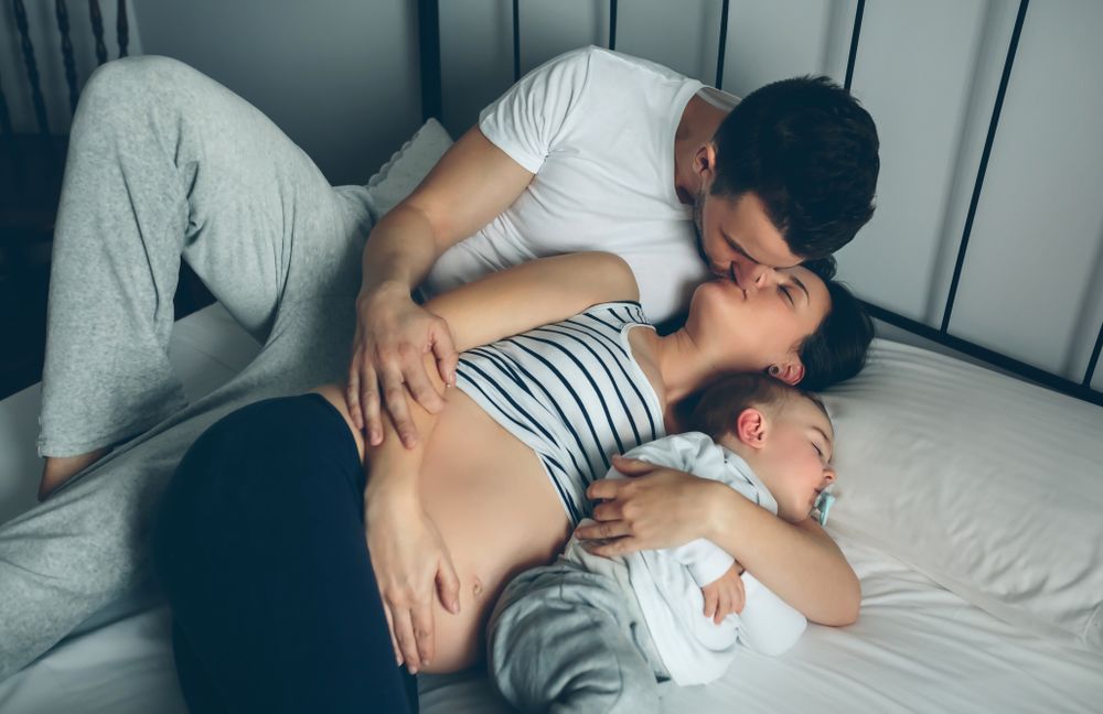 Pregnant woman kissing her partner with their son